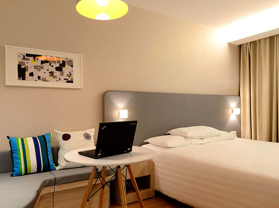 Ein Hotelzimmer. In der mitte ein kleiner Tisch mit Laptop